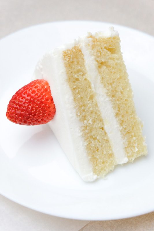 Vegan white cake - vegan vanilla cake made from a fluffy spongecake with white frosting and a strawberry. 