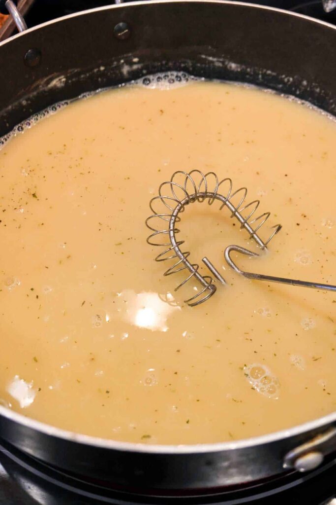 Vegan gravy with herbs in a pan.