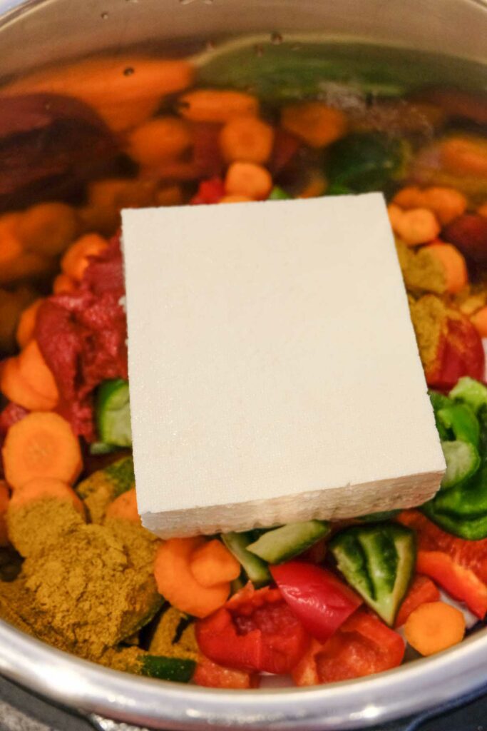 Adding all the ingredients to the Instant Pot: bell pepper, tofu, tomato paste, water and curry powder.