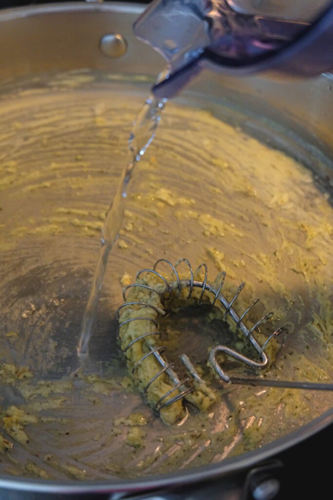 Water being poured into a gravy mixture in a pan.