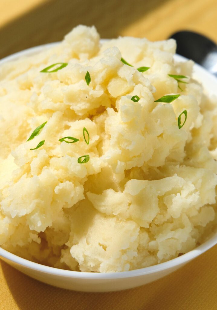 Close up view of a bowl of mashed potatoes with sliced green onions.